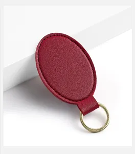Llavero de cuero PU ovalado rojo vino con anillo dorado, accesorio elegante minimalista.