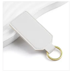 Close-up detail of white PU leather keychain with gold metal ring, minimalist blank pendant.