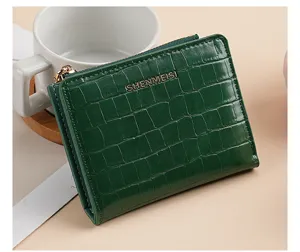 Primo piano di dettaglio di un elegante portafoglio corto verde con motivo coccodrillo.
