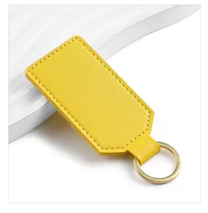 Detailed shot of bright yellow PU leather keychain with white stitching and gold metal ring.