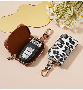 Étui pour clés de voiture en cuir à imprimé léopard avec fermeture éclair et crochet métal.