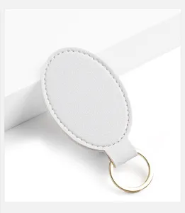 Primer plano del llavero ovalado de piel sintetica blanca virgen con anillo dorado.