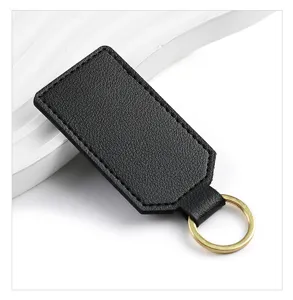 Close-up detail of black PU leather keychain with gold metal ring, minimalist style.