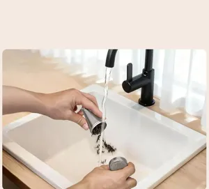 Dettaglio dell'infusore per tè in acciaio inossidabile risciacquato sotto il rubinetto.