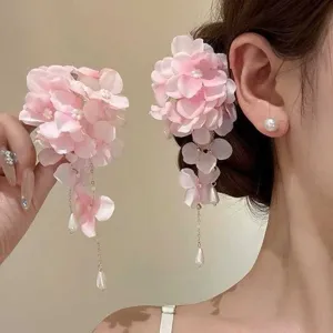Detalle de horquilla de flores de tela rosa con elegantes borlas largas y perlas