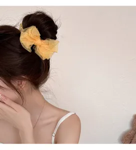 Detalle de una pinza para el pelo con lazo de malla a cuadros amarillos en un moño