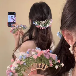 Close-up of elegant colorful gypsophila flower hair pin with golden base for bridal wear.