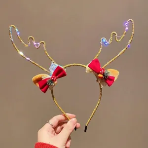 Primer plano de la diadema de astas de reno con LED, lazos rojos y luces brillantes