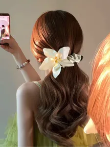 Elegante weiße Blumen-Bananenspange, gestylt in einem niedrigen Pferdeschwanz