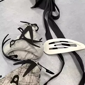 Close-up of oversized white snap hair clip and black creative scissor props on floor