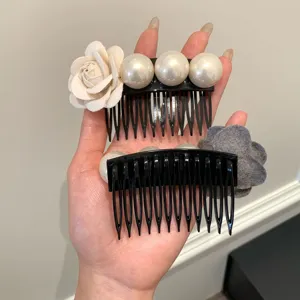 Close-up of elegant flower and pearl hair combs with black plastic teeth for women