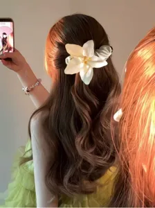 Detaillierte Nahaufnahme einer eleganten weißen Stoffblumen-Bananenspange im Haar