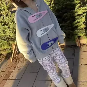 Model wearing three oversized colorful giant snap hair clips on a grey zip-up hoodie