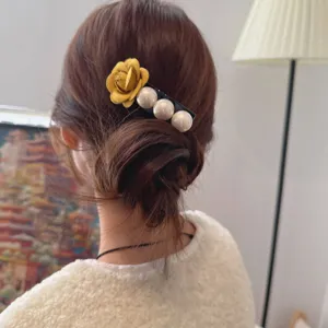Close-up view of elegant hair comb featuring a yellow fabric flower and pearls in a bun