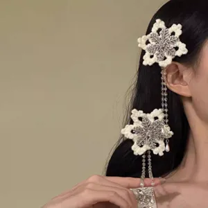 Close-up of white crochet snowflake hair clips with rhinestone tassels on long black hair