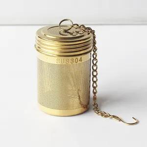 Detailaufnahme des goldenen Tee-Siebs aus Edelstahldraht mit Kette und Haken zum Aufbrühen.