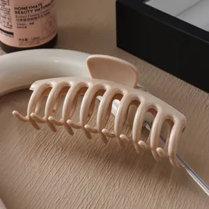 Primer plano de una pinza para el cabello de silicona beige brillante con diseño curvo suave