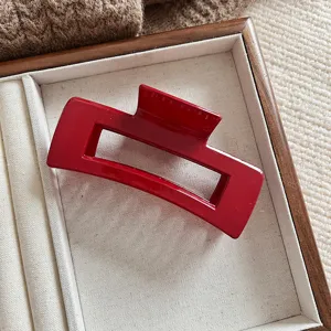Detalle de una pinza de pelo rectangular roja grande colocada en una bandeja de madera