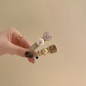 Elegant retro-style hair clips decorated with pearls and rhinestones held in hand