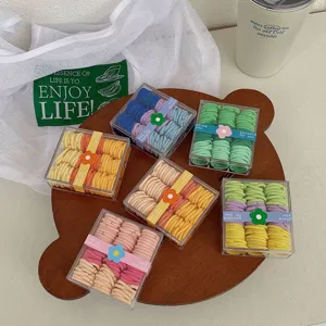 Gomas de pelo arcoíris pastel en cajas trasparentes con etiquetas de flores en bandeja.