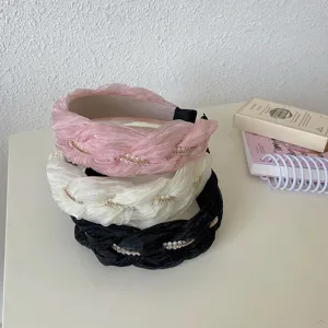 Detailopname van drie elegante gevlochten haarbanden met parel- en strasaccenten.