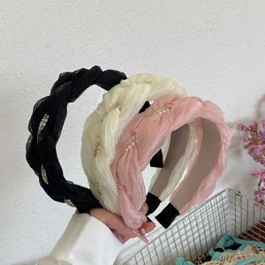 Detail van drie elegante gevlochten Franse haarbanden met geplooide stof en parels.