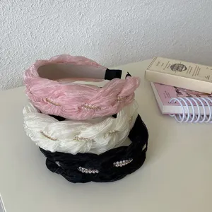 Detailopname van drie geplooide gevlochten haarbanden met parels in diverse kleuren