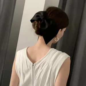 Rear view of an elegant oversized black satin bow hair clip on a low bun hairstyle.
