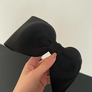 Macro view showing the fabric texture of an oversized elegant black bow hair clip.