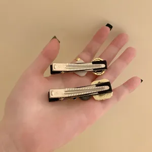 Detailed back view of vintage pearl rhinestone duckbill hair clips held in hand