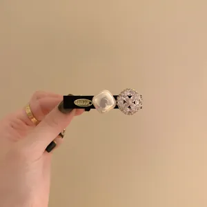 Detailed view of elegant hair clip with pearl and rhinestone accents on black base.