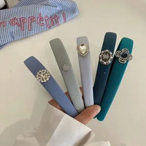 Elegant variety of jeweled fabric headbands in shades of blue and grey held by hand