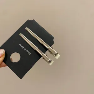 Vista macro di due fermagli per capelli minimalisti in metallo argento su carta nera
