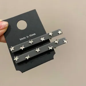 Primo piano di due fermagli per capelli grigi con strass a stella su cartoncino nero