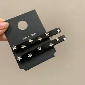 Primo piano di fermagli per capelli neri con strass a stella su cartoncino