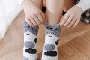 Nahaufnahme von kuscheligen Korallenfleece-Socken mit niedlicher Katzenstickerei