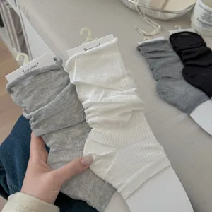 Close-up showing the soft silk texture of ballet-style slouch leg warmers in grey and white