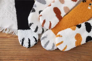 Nahaufnahme von flauschigen Korallenvlies-Socken mit süßen Katzenpfotenmustern und Stickerei