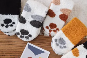 Nahaufnahme von flauschigen Korallenvlies-Socken mit bunten Katzenpfoten-Mustern