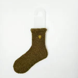 Nahaufnahme einer olivgrünen Korallenvlies-Socke mit gelber Herzstickerei im Detail