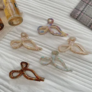 Detailed macro view of assorted color bow-shaped acetate hair claw clips on textured fabric