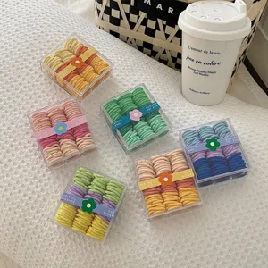 Seis cajas de elásticos para el cabello de colores sobre un fondo suave con textura