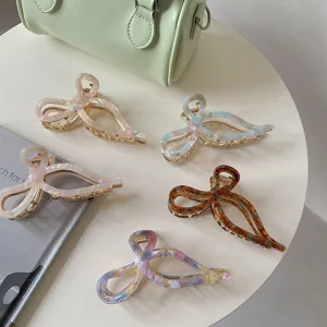 Detailed view of elegant acetate and gold alloy bow-shaped hair claw clips on a table