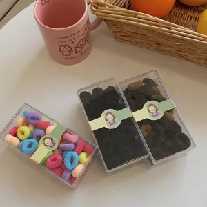 Set of three boxes of colorful and black elastic hair ties for kids in cute packaging