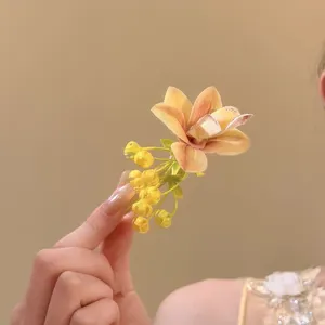 Close-up of yellow orchid flower hair clip with realistic floral details