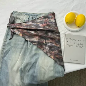 Dettaglio di un foulard leopardato metallico usato come accessorio in vita sui jeans.