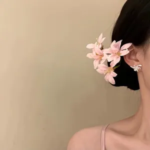Vista dettagliata elegante di accessori per capelli e orecchini a fiori rosa indossati da modella