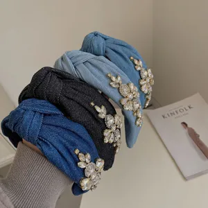 Close-up of luxury knotted denim headbands with sparkling rhinestone flower clusters