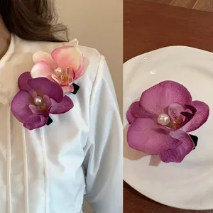 Elegant detail view of realistic orchid flower hair clips featuring a pearl center