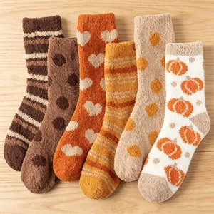 Soft coral fleece fuzzy socks with heart, pumpkin, and stripe patterns on wood